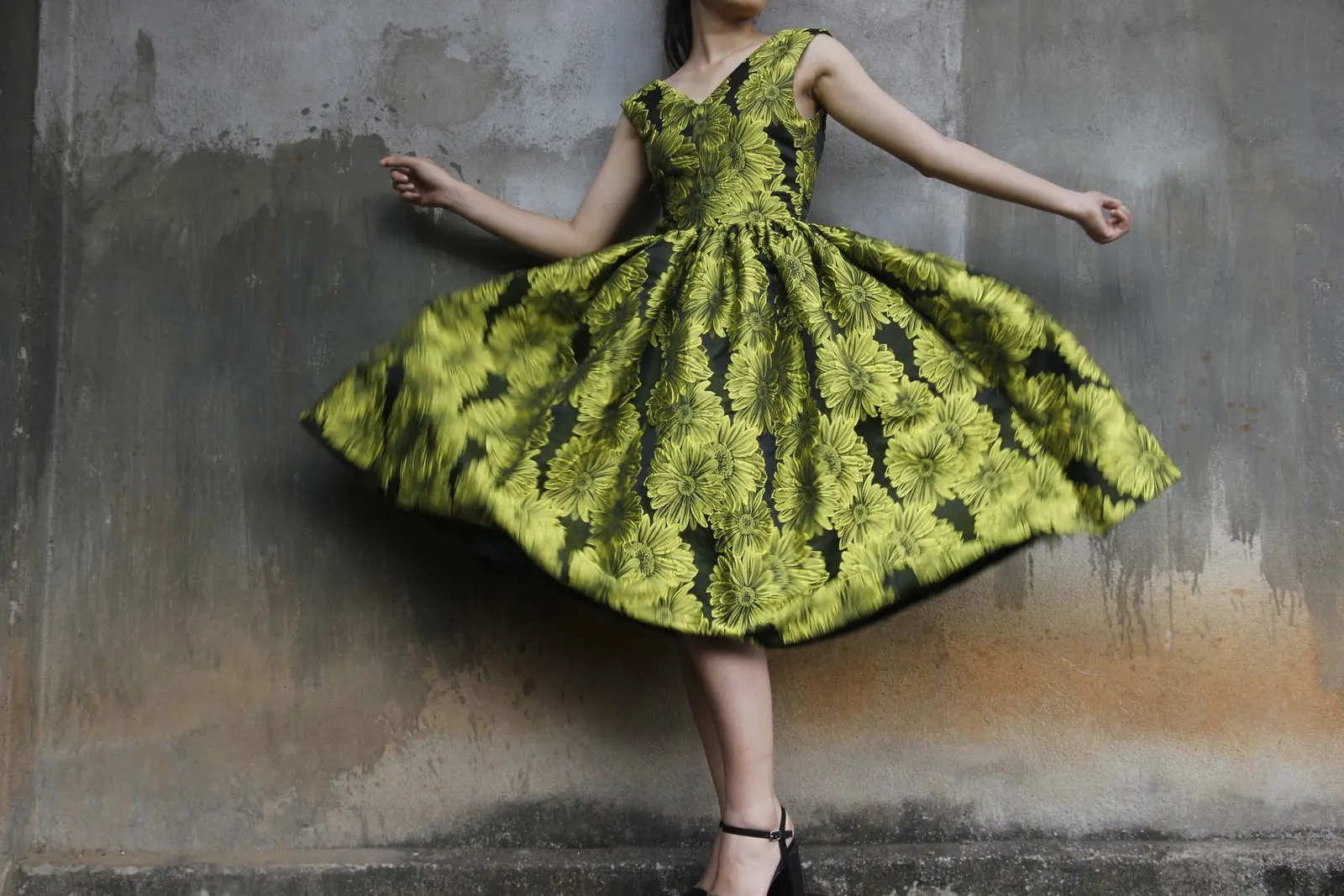 A green floral dress in motion against a textured wall