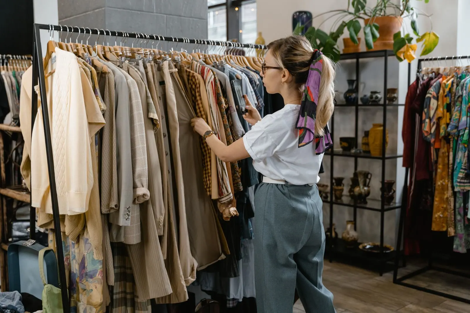 A shopper comparing tailored trousers and jackets on a boutique rail